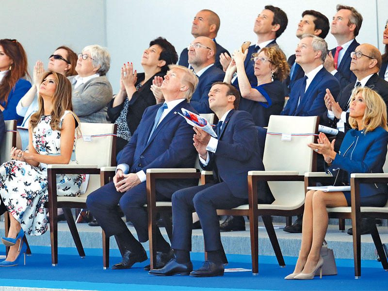 ماكرون وترامب وزوجتاهما يتابعون العرض الجوي في وسط باريس أمس (رويترز)