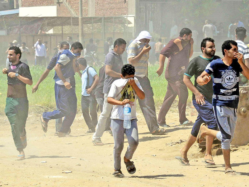 أهالٍ يفرون من الغاز المسيل للدموع خلال اشتباكات مع قوات الأمن بالوراق أمس   (الجريدة)