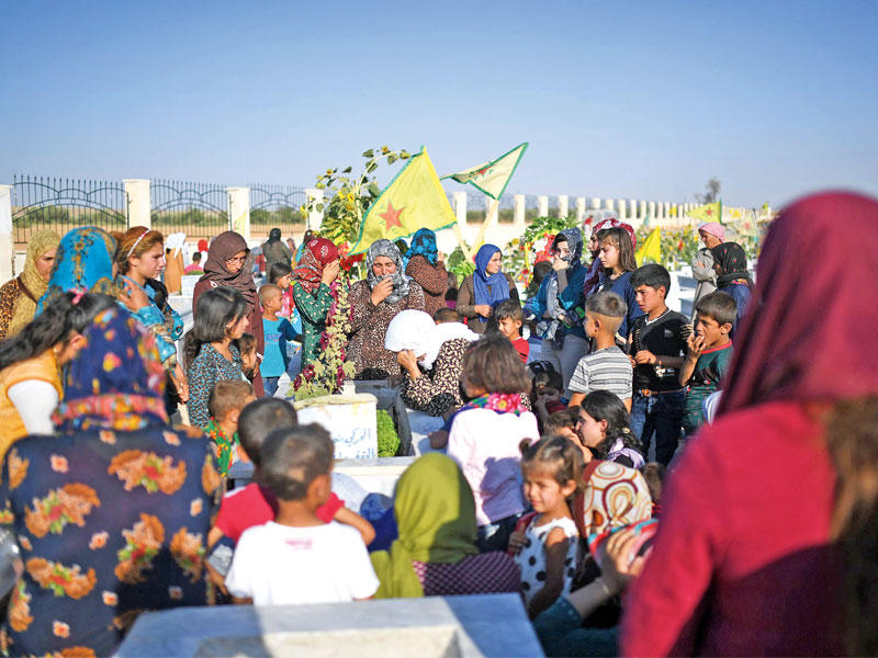 كرديات يزرن ذويهن بمقبرة كوباني أمس الأول     (أ ف ب)