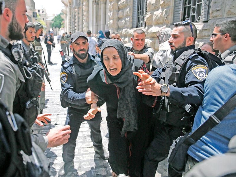 عناصر من حرس الحدود الإسرائيليين يعتدون على مقدسية قرب إحدى بوابات الاقصى أمس   (أ ف ب)