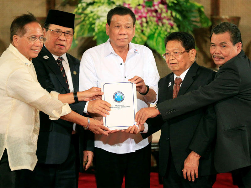 الرئيس الفلبيني رودريغو دوتيرت ورئيس جبهة مورو للتحرير الإسلامي الحاج مراد إبراهيم ، يسوع دوريزا أمين عملية السلام، غزالي جعفر نائب رئيس جبهة تحرير مورو الإسلامية، ومهاجر إقبال رئيس لجنة السلام التابعة لجبهة مورو للتحرير الاسلامى