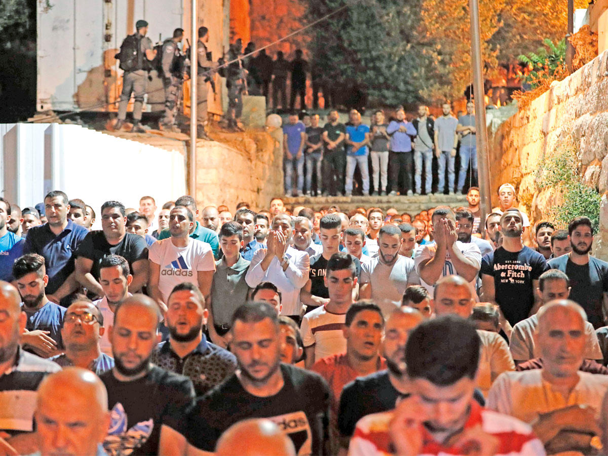 مقدسيون يؤدون الصلاة في الشوارع المؤدية للمسجد الأقصى بالمدينة المقدسة مساء أمس الأول (أ ف ب)