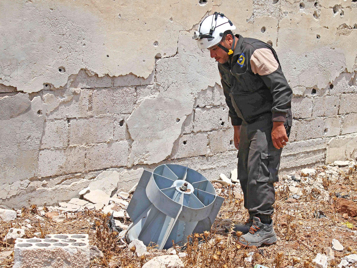 أحد متطوعي «الخوذ البيضاء» يتفقد بقايا قنبلة لم تنفجر في منطقة درعا أمس (أ ف ب)