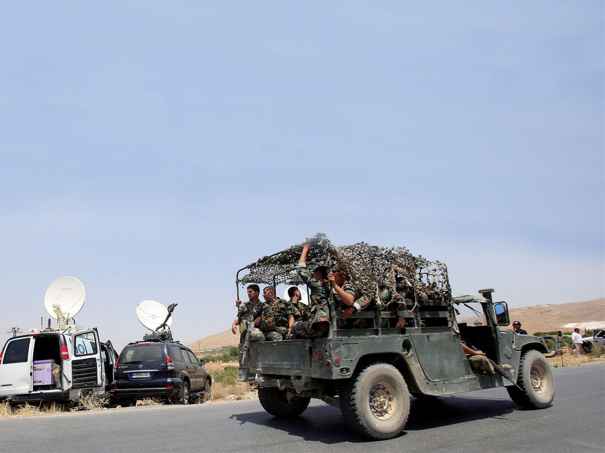 آلية للجيش تمر أمام سيارات تابعة لوسائل إعلام على مدخل عرسال أمس (رويترز)n