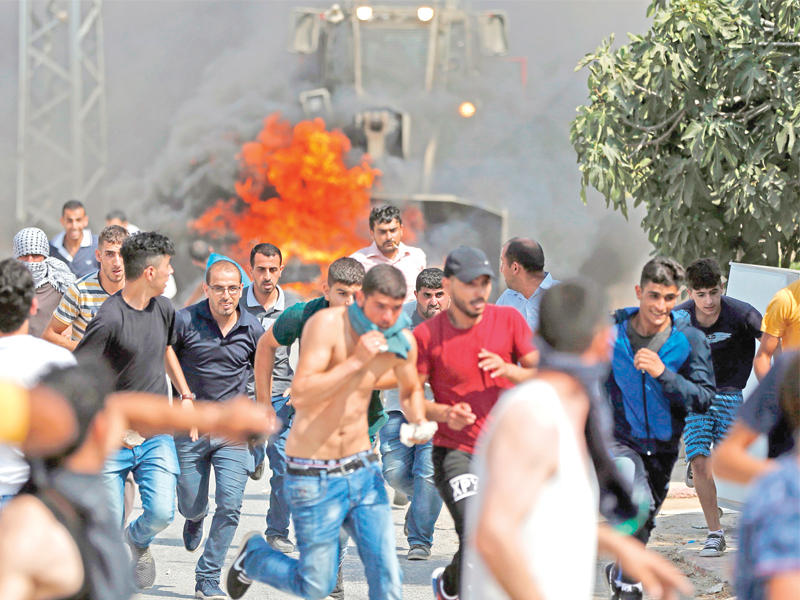 فلسطينيون يتصدون لبلدوزر للجيش الإسرائيلي غرب رام الله أمسt (أ ف ب)
