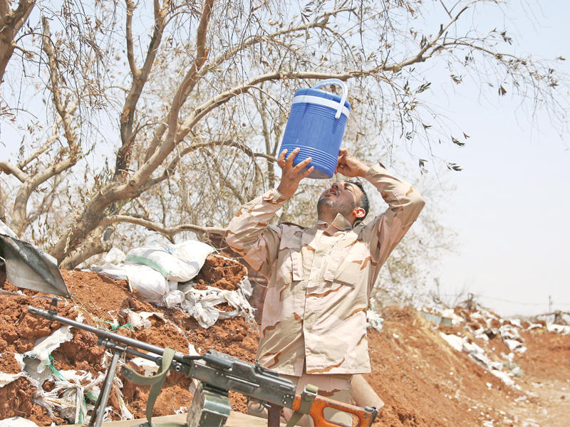 مقاتل من الجيش الحر يشرب المياه على جبهة الغارية الجنوبية بمحافظة درعا أمس  (رويترز)
