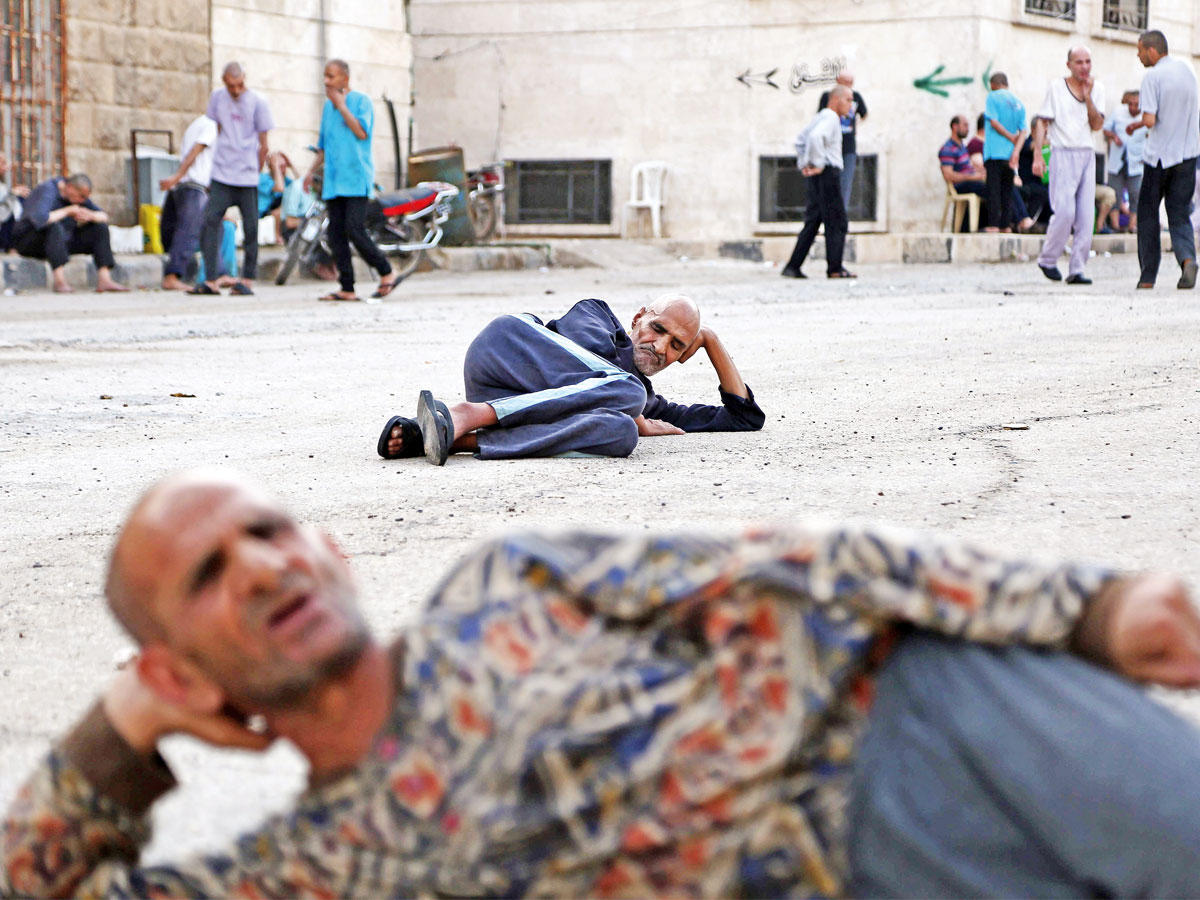 يشهد مستشفى الأمراض النفسية والعقلية، الوحيد من نوعه في مناطق سيطرة فصائل المعارضة في شمال سورية، ارتفاعا في عدد رواده منذ اندلاع النزاع في مارس 2011.nوينتظر مرضى عراة، في مجموعات، أن يحين دورهم الواحد تلو الآخر للحلاقة والاستحمام داخل مبنى حجري من ثلاثة طوابق في مدينة أعزاز، شمال حلب، يؤوي 139 شخصا، بينهم 32 امرأة، تم نقله مرتين بفعل الحرب، التي تسببت لهم ولغيرهم من مختلف الفئات في اضطرابات نفسية وحالات اكتئاب وصدمة، جراء تجارب دامية عاشوها، وهول مشاهد تعرضوا لها.nوفي الصورة، مرضى يرقدون ويتجولون في ساحة المستشفى بأعزاز، بالقرب من الحدود مع تركياnفي 6 يونيو الماضي.  (أ ف ب) n