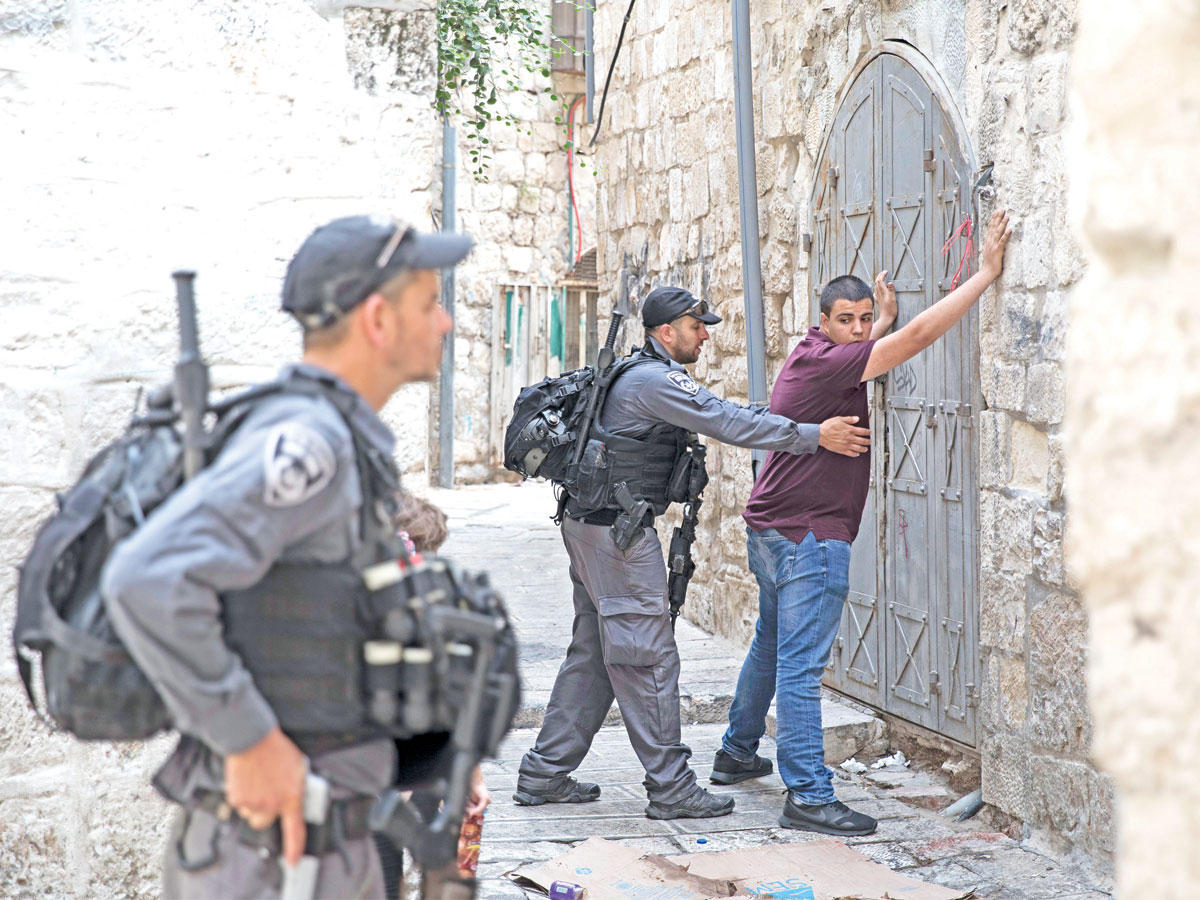 جنديان إسرائيليان يفتشان فلسطينياً في القدس القديمة (أي بي أيه)