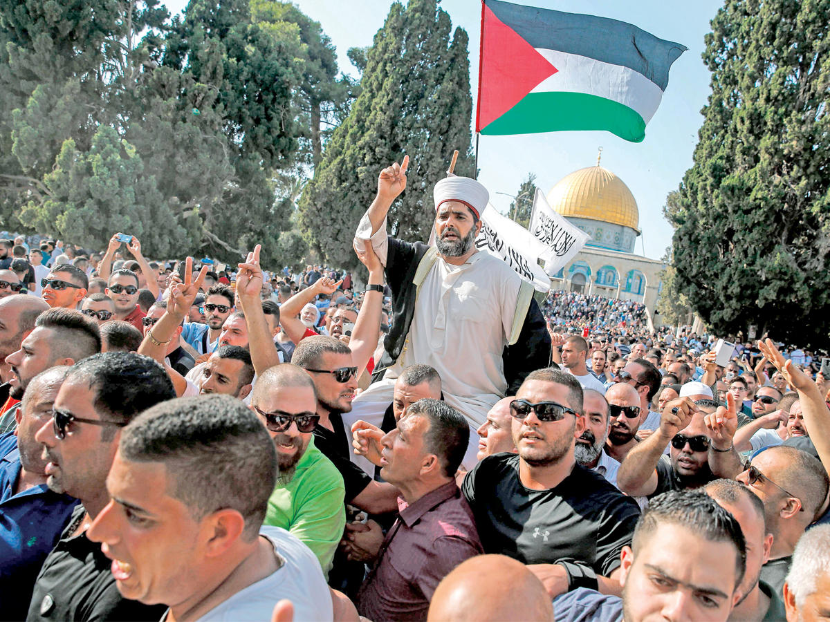 فلسطينيون يحملون علماً فلسطينياً ومدير المسجد الأقصى عمر كسواني في باحة الحرم القدسي في القدس أمس (أ ف ب)