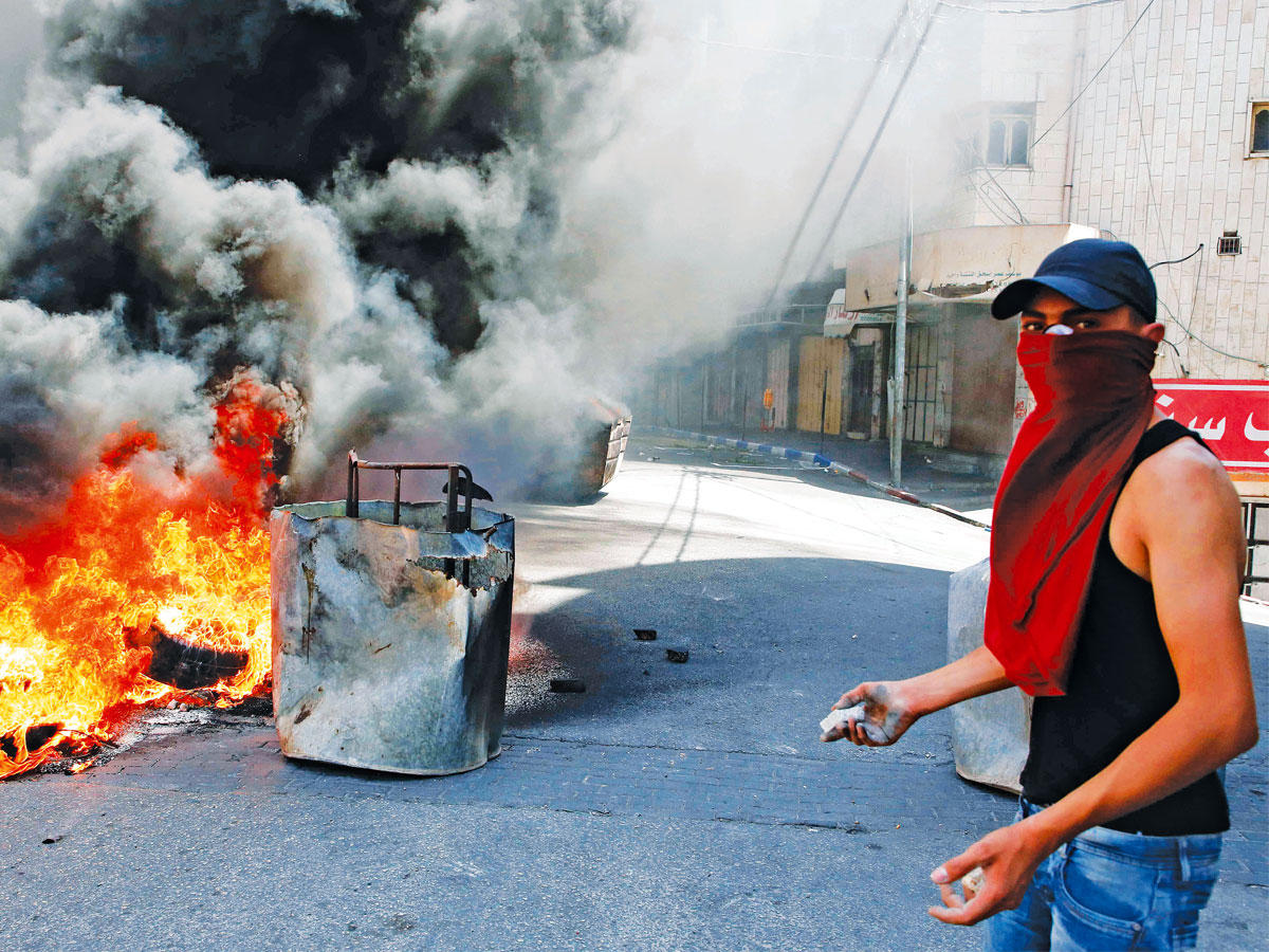 فلسطيني خلال مواجهات في الخليل بالضفة الغربية أمس (أ ف ب)n