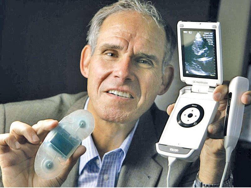 الطبيب إيريك توبول ممسكاً بهاتفه وجهاز تخطيط القلب