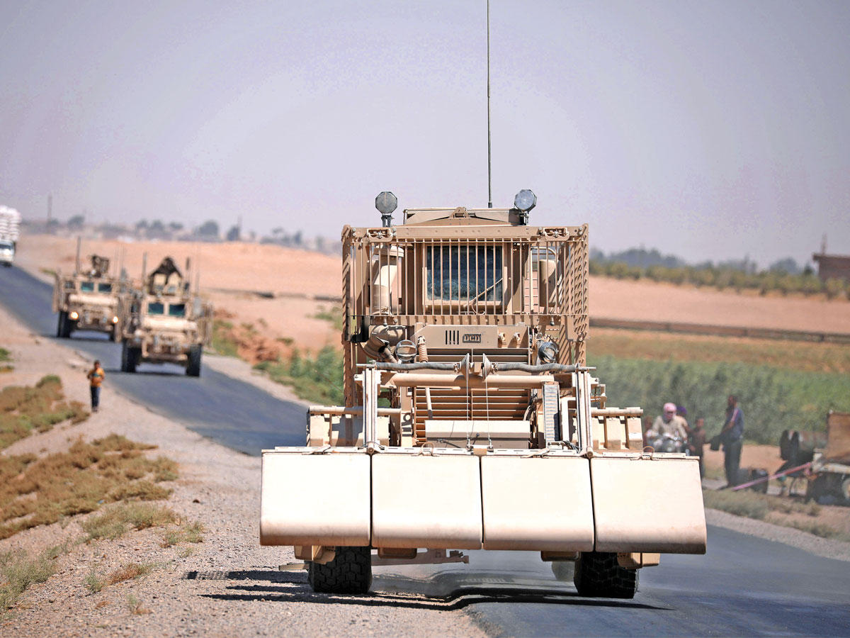 آلية إزالة تتقدم قافلة عسكرية على طريق الرقة الرئيسي أمس (رويترز)