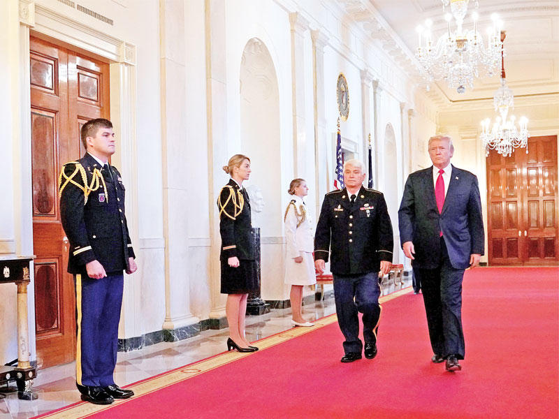 ترامب وجيمس مكلاوغن الذي خدم في فيتنام قبل تسليمه ميدالية الشرف في البيت الأبيض أمس (رويترز)