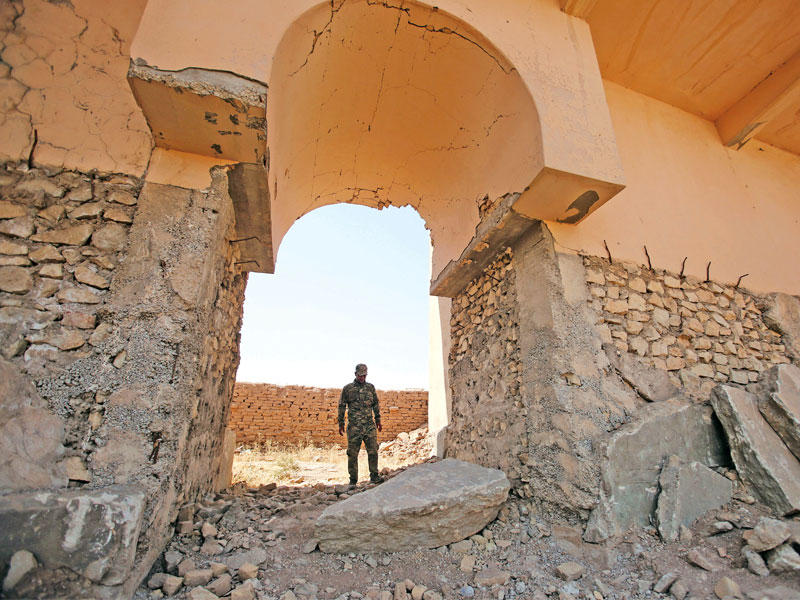 أحد أفراد قوات الأمن العراقية يتفقد رفات لوحات الحائط وتماثيل هائلة من الثيران المجنحة دمرها مسلحو تنظيم داعش في مدينة نمرود الآشورية على الضفة الشرقية لنهر دجلة أمس الأول  (رويترز)