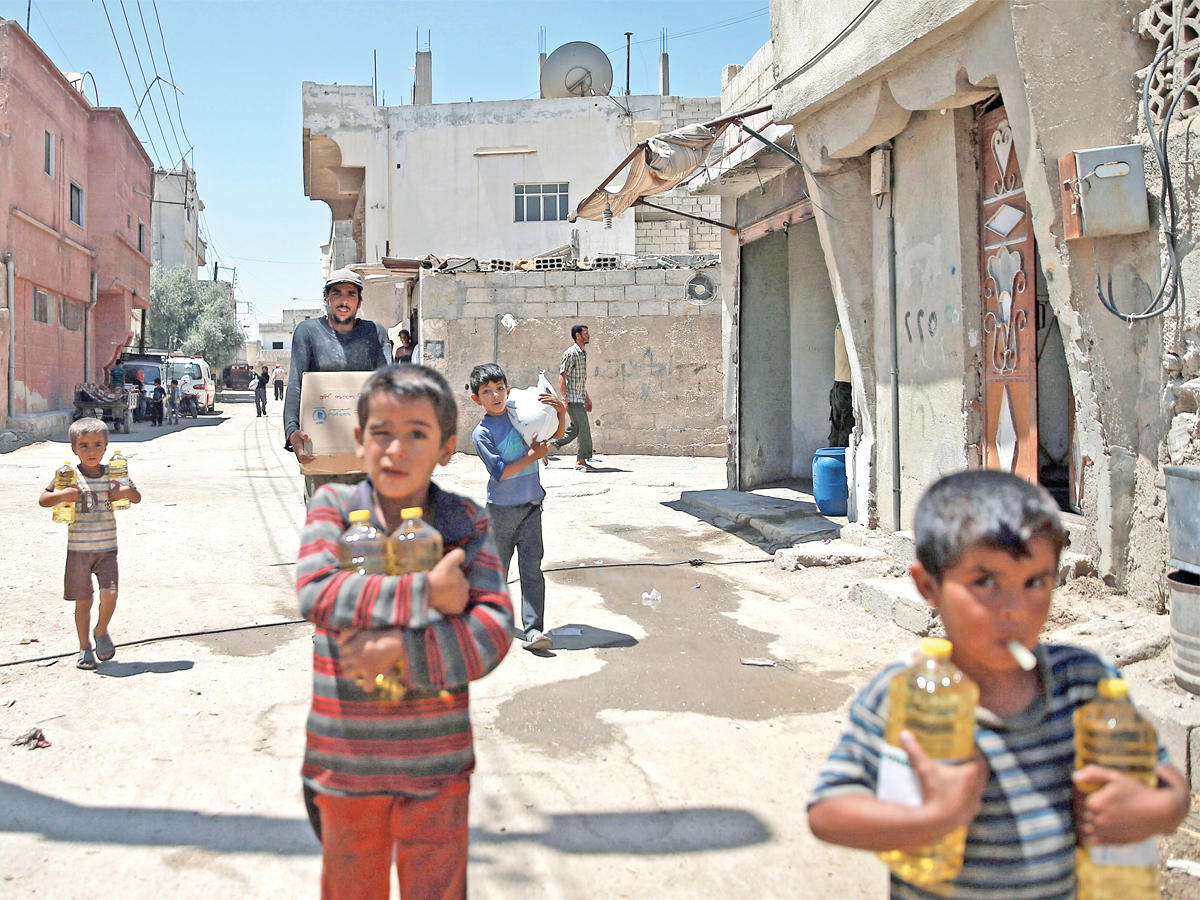 صبية يحتضنون معونة غذائية في دوما  اليوم (رويترز)