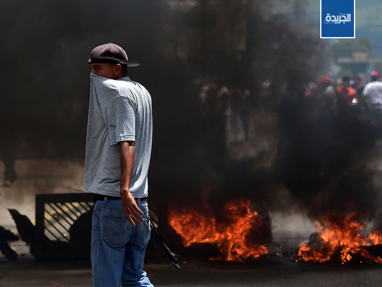 معارض يقف بالقرب من حاجز يحرق لهيب في مدينة فالنسيا