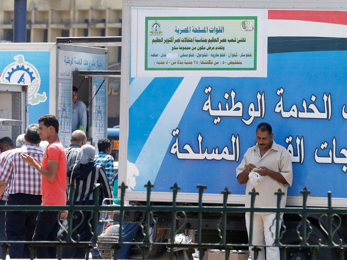 مصريون في محيط شاحنات بيع المواد الغذائية التابعة للقوات المسلحة بميدان رمسيس وسط القاهرة أواخر يوليو الماضي (رويترز)