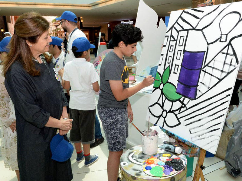 سميرة عمر تطالع نشاط الرسم لأحد الطلاب المشاركين في الدورة