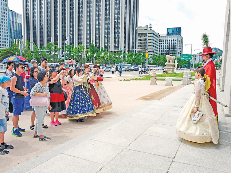 سياح يلتقطون الصور في وسط مدينة سيول أمس (إي بي إيه)