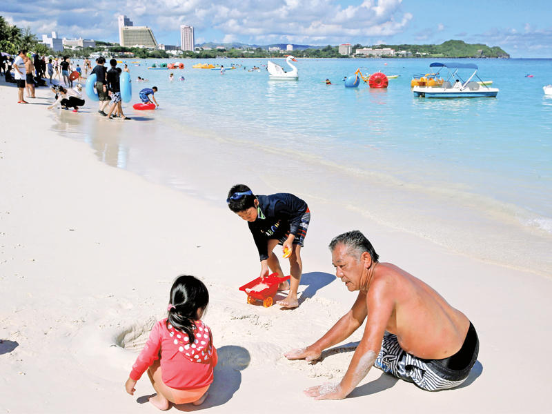 مصطافون يستمتعون بالشاطئ في منطقة تومون بجزيرة غوام في المحيط الهادئ أمس (رويترز)