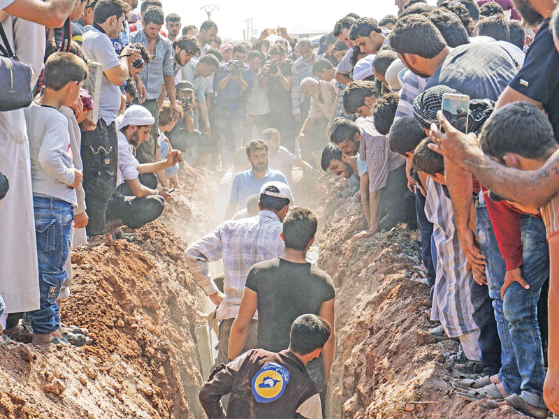 عناصر من «الخوذ البيضاء» يجهزون لدفن زملائهم بحضور حاشد في سارمين أمس  (أ ف ب)