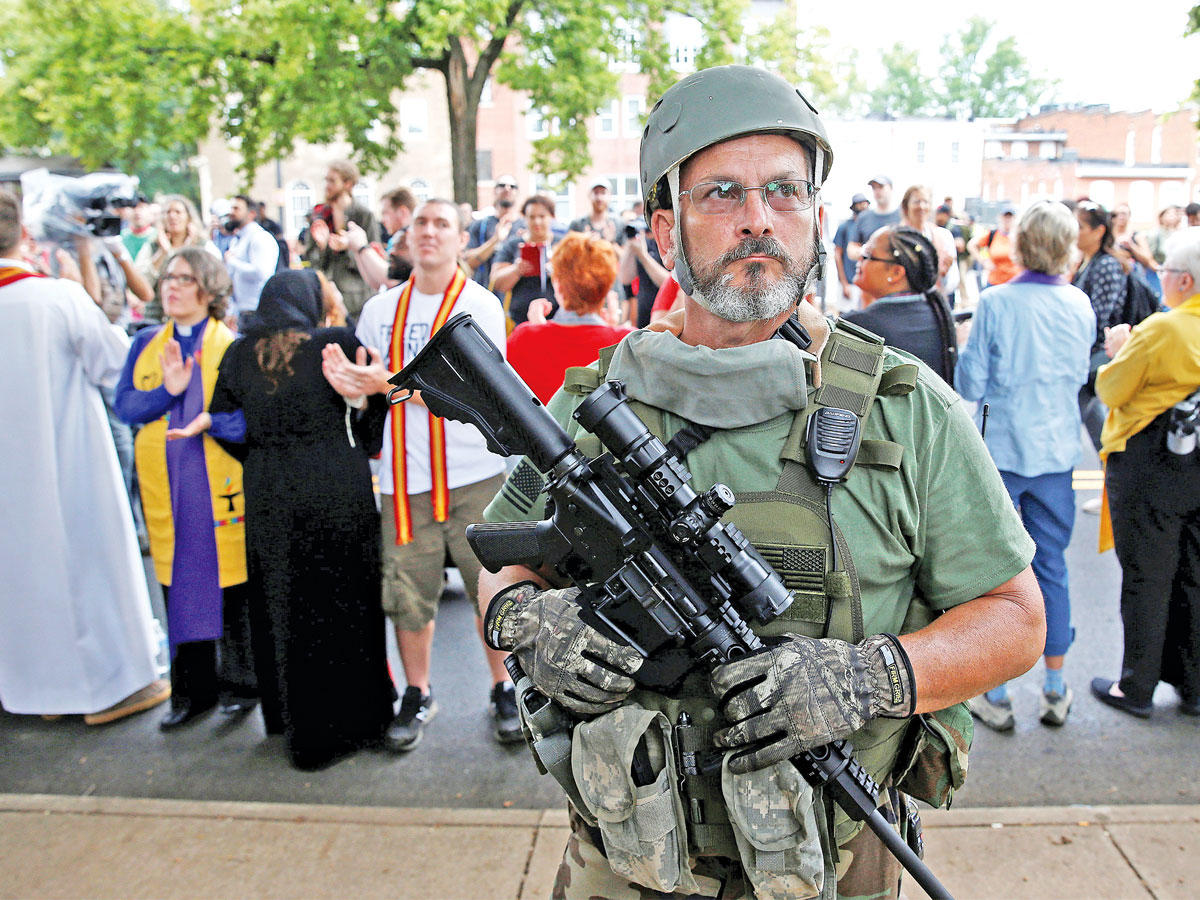 يميني أمريكي متطرف مناد بسيادة العراق الأبيض يحمل سلاحه امام تجمع لرجال دين معارضين للعنصرية في فيرجينيا أمس (رويترز)