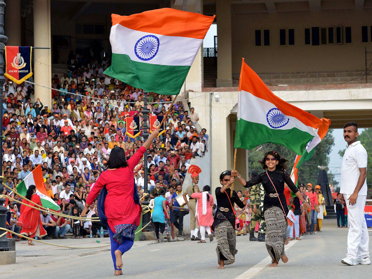 فتيات هندية ترفع الأعلام الوطنية خلال حفل ليلا على الحدود الهندية الباكستانية