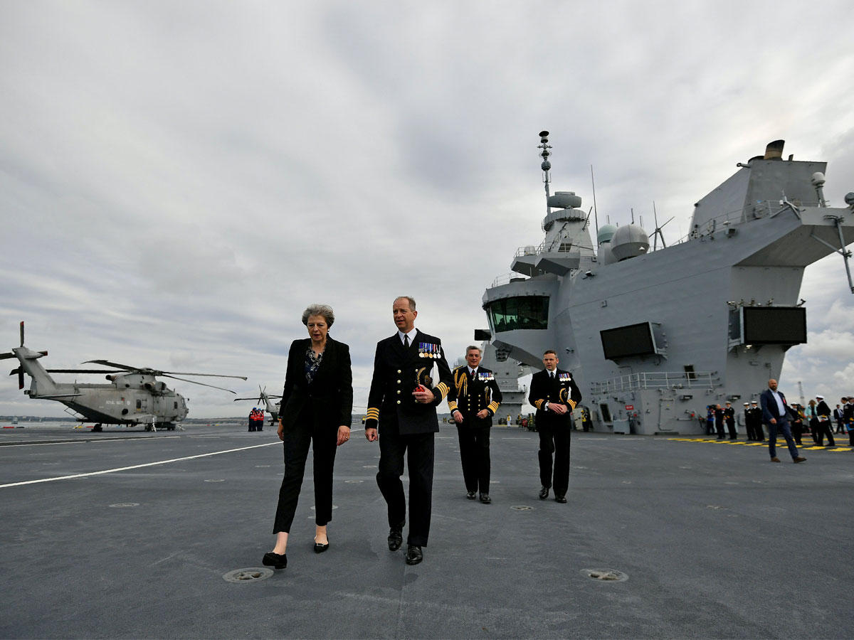 رئيسة الوزراء البريطانية تيريزا ماي مع الكومندور جيري كيد، نقيب حاملة الطائرات البريطانية همس كوين إليزابيث، خلال جولتها في السفينة، بعد أن وصلت إلى قاعدة بورتسموث البحرية