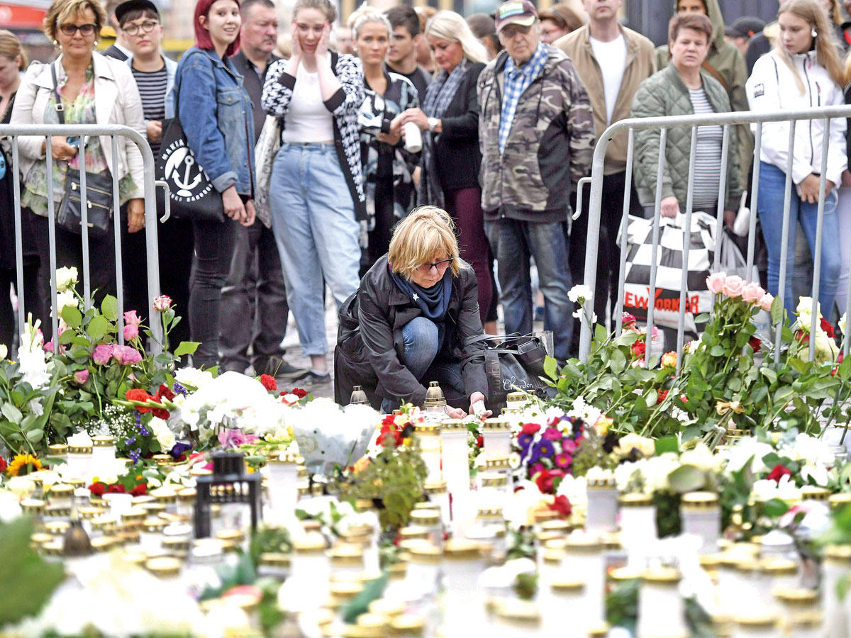 فنلندية تضع الزهور بموقع عملية الطعن بساحة سوق توركو (أ ف ب)
