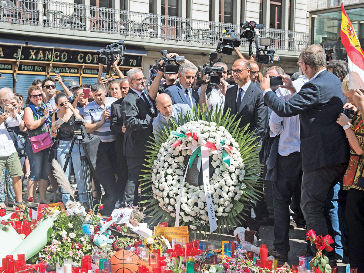 وزير الخارجية الإيطالي أنجيلينو ألفانو يضع إكليلاً من الزهور عند الموقع الذي شهد هجوم الدهس وسط برشلونة أمس (رويترز)