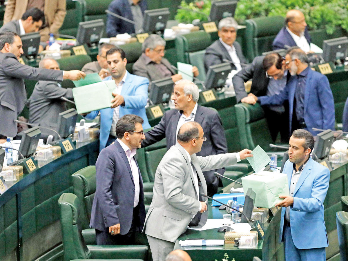 نائبان يدليان بصوتيهما أثناء جلسة منح الثقة للحكومة الجديدة بمجلس الشورى في طهران أمس  (رويترز)
