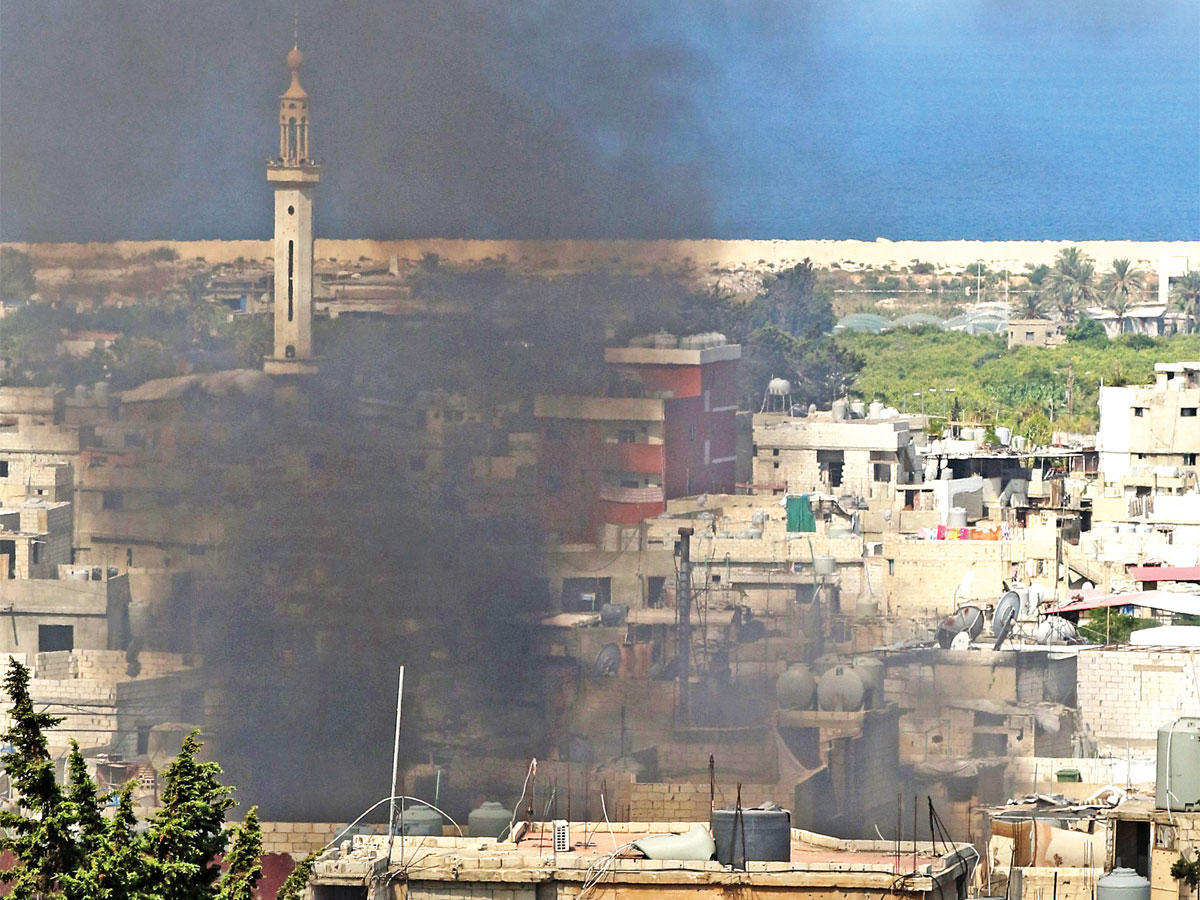 دخان يتصاعد من مخيم عين الحلوة بمدينة صيدا بعد مواجهات بين فصائل فلسطينية ومتطرفين أمس  ( أ ف ب)