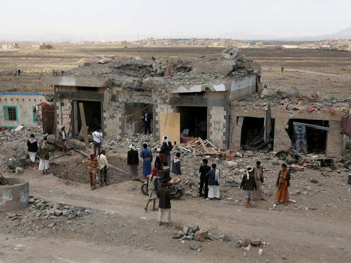 يمنيون عند نقطة خاضعة لسيطرة الميليشيات الحوثية استهدفتها مقاتلات التحالف أمس شمال صنعاء (رويترز)