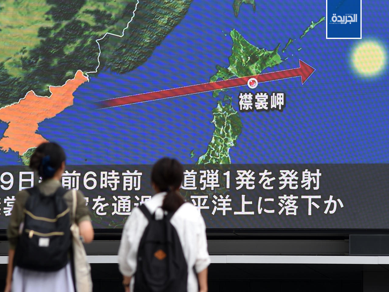 يابانيون يشاهدون الأخبار على شاشة ضخمة تعرض خريطة لليابان وشبه الجزيرة الكورية