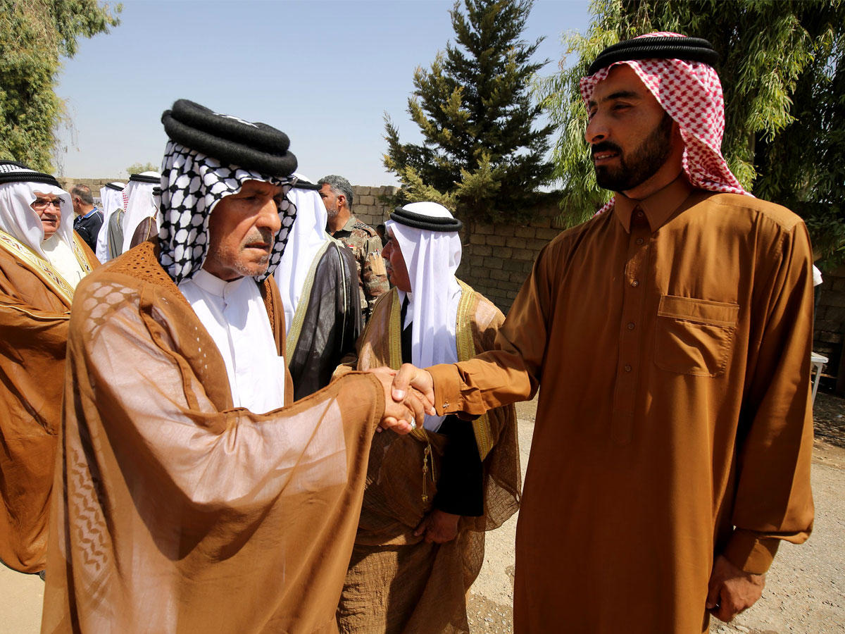 عراقيان يتصافحان قبل اجتماع لزعماء القبائل في الموصل أمس            (أ ف ب)