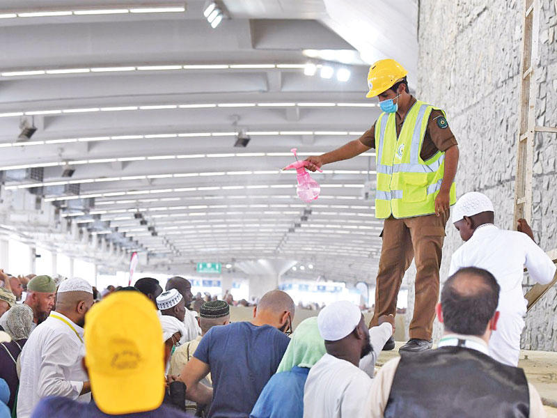 جندي سعودي يرش الماء لتخفيف وطأة الحر عن رماة الجمرات أمس (واس)