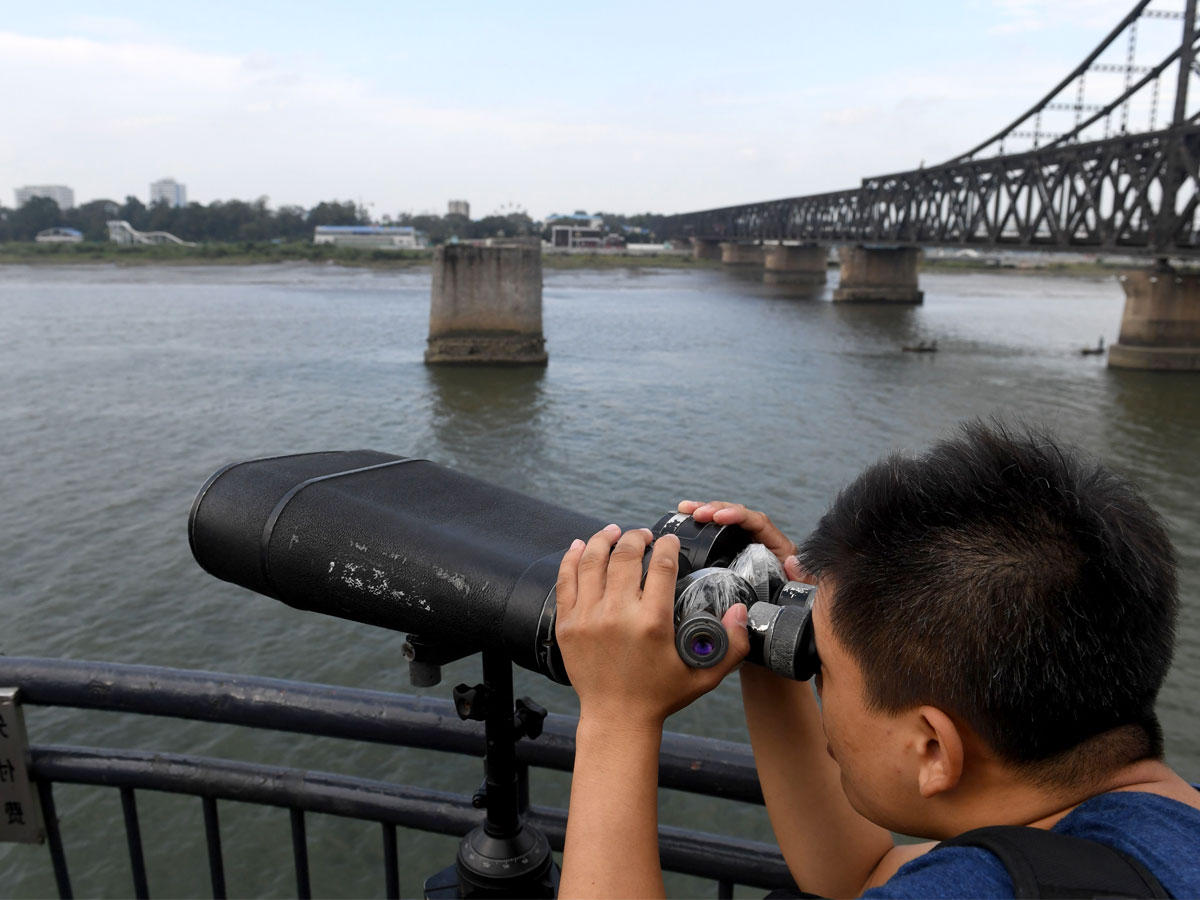 سائح صيني يراقب الجانب الكوري الشمالي أثناء زيارة للجسر المكسور من جانب مدينة دانغدونغ أمس (أ ف ب) 