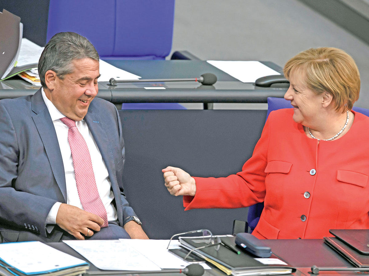 ميركل تتحدث لوزير الخارجية سيغمار غابرييل خلال جلسة البرلمان في برلين أمس  (إي بي إيه)