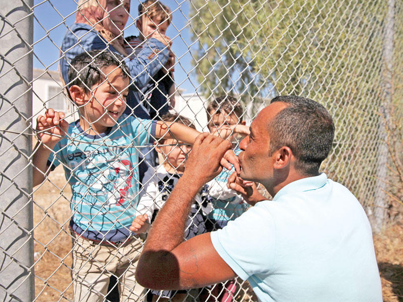 سوري يعيش في قبرص يقبل يد نجله بعد وصوله مع عائلته إلى مخيم اللاجئين في كوينوتريميثيا خارج نيقوسيا أمس (رويترز)
