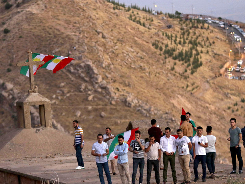 أكراد يحملون أعلام كردستان قرب كنيسة في منطقة عقرة أمس الأول                        (أ ف ب)