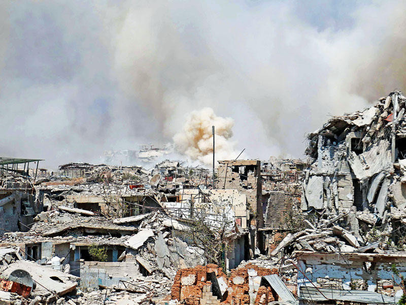 دخان يتصاعد وسط المباني المدمرة بمناطق سيطرة المعارضة في حي جوبر شرق دمشق أمس  (أ ف ب)