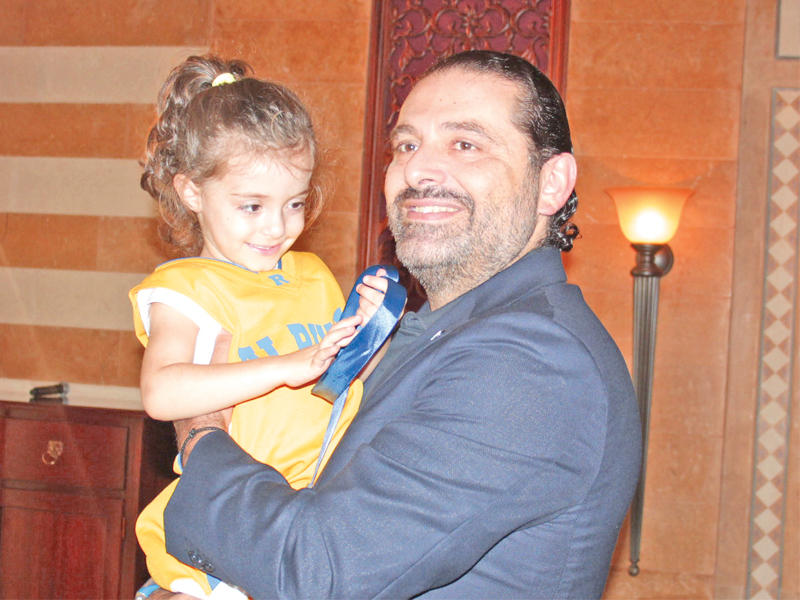 رئيس الحكومة اللبنانية سعد الحريري يحمل طفلة خلال استقباله مشجعي نادي الرياضي لكرة السلة في بيروت أمس (دالاتي ونهرا) 