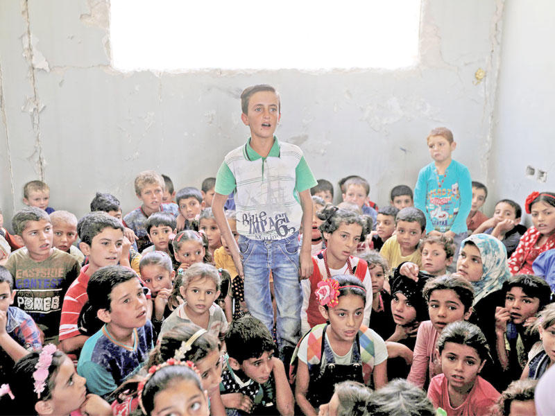 تلاميذ يفترشون الأرض في أحد فصول مدرسة الصفانية المدمرة بريف حلب الشرقي أمس الأولt(رويترز)