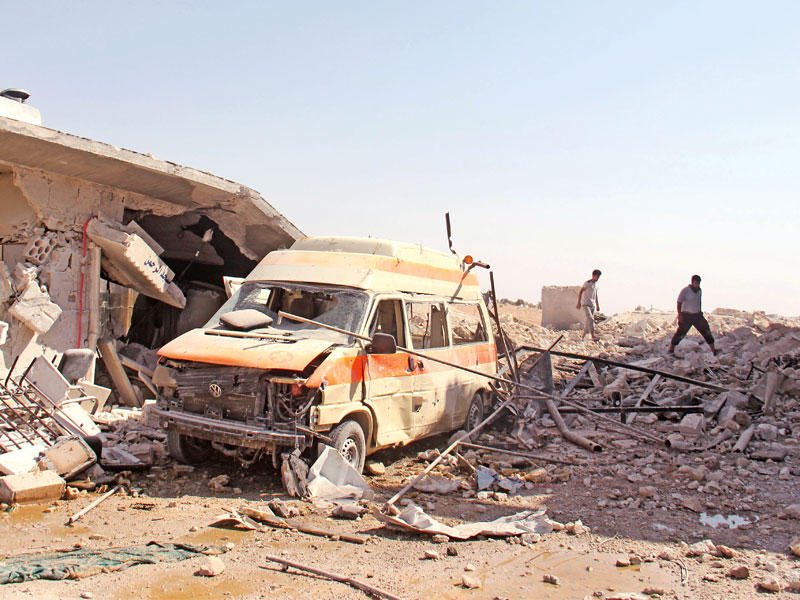 سوريان يتفقدان آثار غارة نظامية على نقطة إسعاف في قرية الطاح غرب إدلب أمس  (أ ف ب)