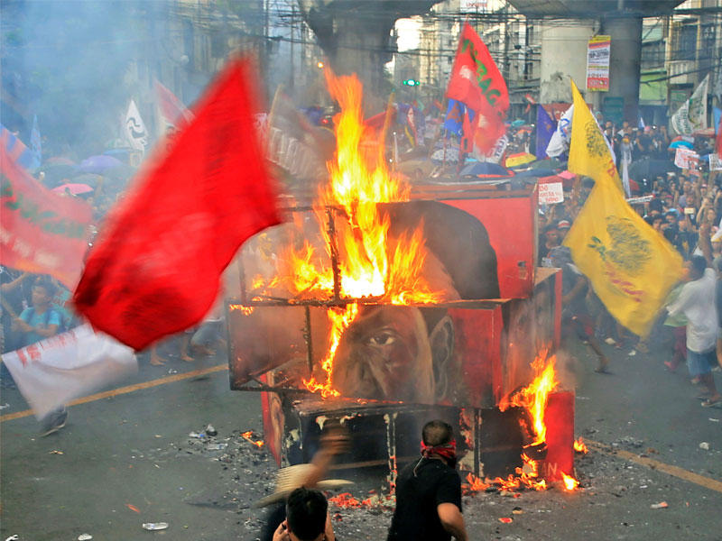 المتظاهرون يحرقون مكعب إيفيغي مع وجه الرئيس رودريغو دوتيرت خلال اليوم الوطني