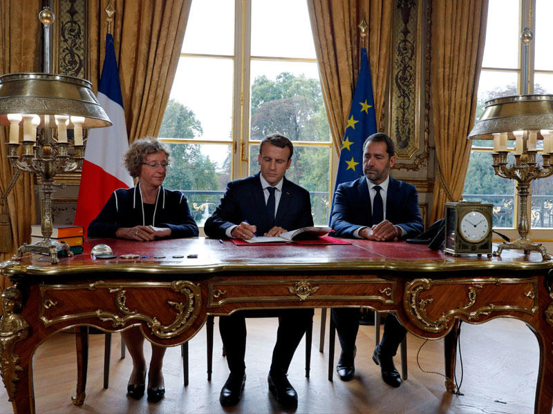 ماكرون يوقع وثيقة القانون في قصر الإليزيه أمس (أ ف ب)