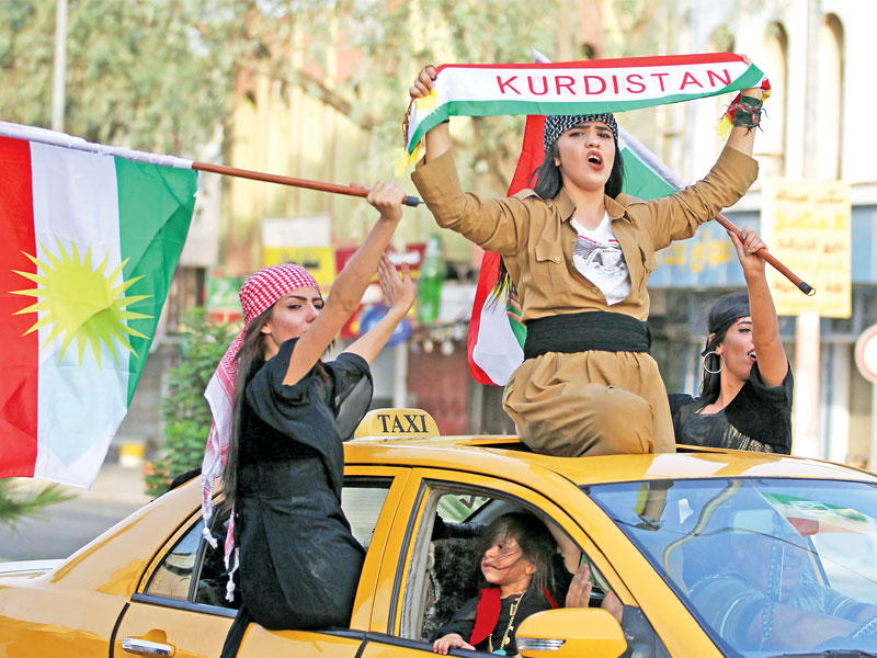 كرديات يرفعن اعلاماً في أربيل أمس (أ ف ب)n