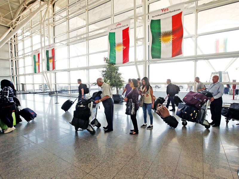 مسافرون أكراد مع أمتعتهم داخل صالة المغادرة في مطار أربيل أمس (رويترز)