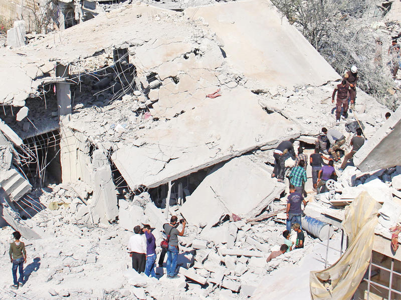 مدنيون سوريون وعاملو إنقاذ أمس في الموقع الذي تعرض لغارة في ارمناز بإدلب (أ ف ب)