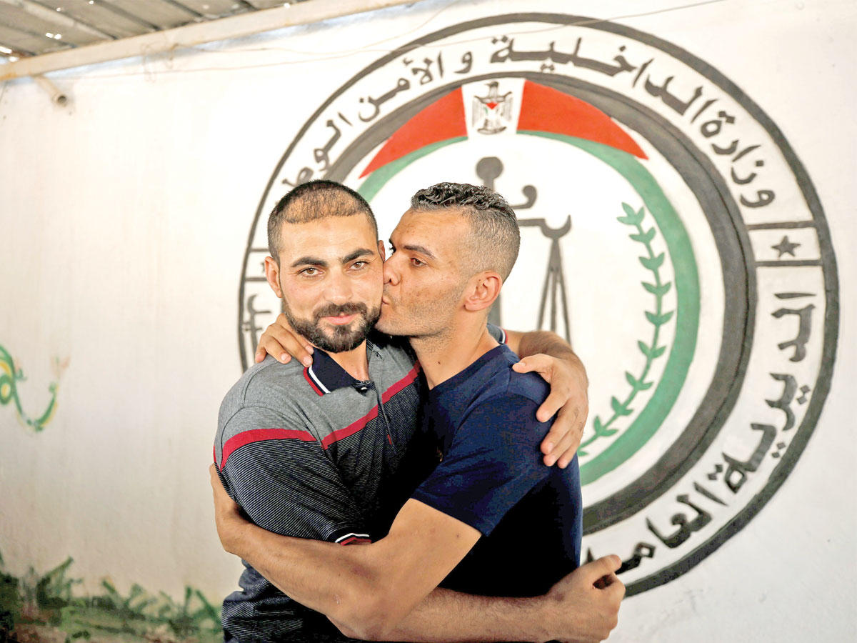 أحد أعضاء «فتح» يعانق ويقبل حارساً بسجن تديره «حماس» عقب الإفراج عنه ضمن تفاهمات المصالحة في غزة أمس (رويترز)
